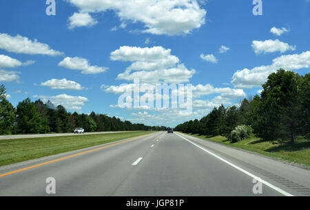 L'autoroute avec des voitures à distance, un ciel ensoleillé avec quelques nuages gonflés Banque D'Images