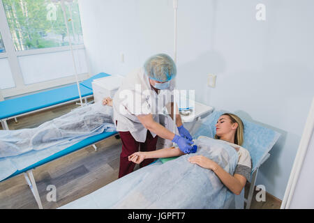 Infirmière professionnelle faire une injection à une femme couchée sur table d'opération à l'hôpital de la préparation médicale anesthésique healthcare surgery concept. Banque D'Images