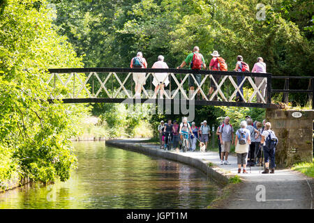 Les gens qui marchent le long du chemin du canal de Llangollen orteil sous le soleil d'été avec d'autres observateurs d'un pont métallique, Llangollen, Wales, UK Banque D'Images