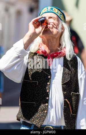 Le Thameside Mummers effectuer un traditionnel mumming play. Un mâle adulte en costume du 14ème siècle environ en prenant un verre de petite bouteille. Banque D'Images