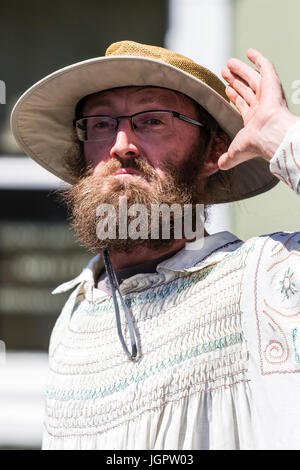 Le Thameside Mummers effectuer un traditionnel mumming play. Un homme mûr en costume du 14ème siècle avec la main de barbus lourdement de côté tête, essayant d'entendre. Gros plan de la tête et des épaules. Banque D'Images