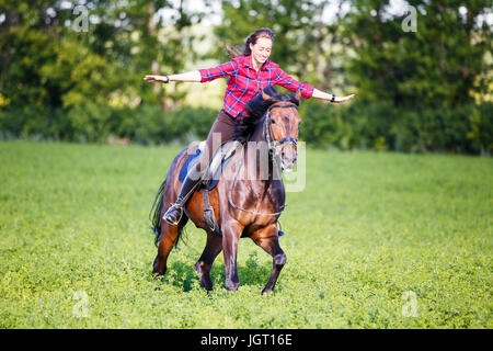 Jeune femme sur cheval au galop sans bride. Free riding equestrian background Banque D'Images