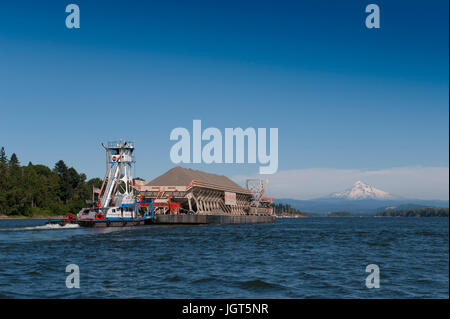 Une pousse du remorquage de la barge chargée jusqu'au fleuve Columbia avec enneigés des mt. Capuche dans la distance Banque D'Images