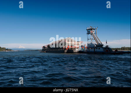 Une pousse du remorquage de la barge chargée jusqu'au fleuve Columbia avec enneigés des mt. Capuche dans la distance Banque D'Images