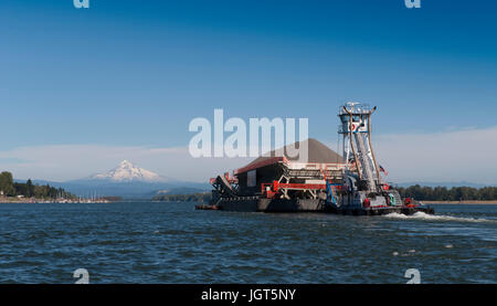 Une pousse du remorquage de la barge chargée jusqu'au fleuve Columbia avec enneigés des mt. Capuche dans la distance Banque D'Images
