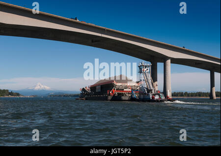 Une pousse du remorquage de la barge chargée jusqu'au fleuve Columbia avec enneigés des mt. Capuche dans la distance Banque D'Images