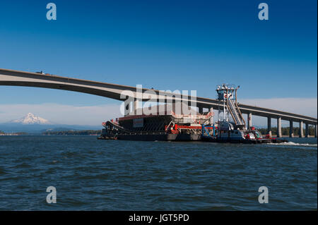 Une pousse du remorquage de la barge chargée jusqu'au fleuve Columbia avec enneigés des mt. Capuche dans la distance Banque D'Images