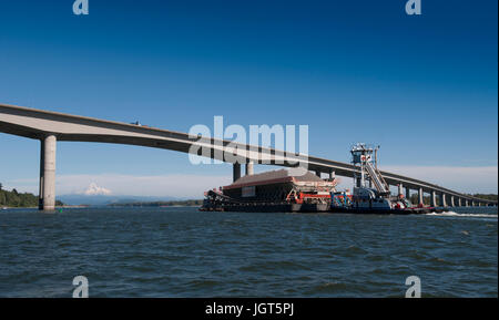 Une pousse du remorquage de la barge chargée jusqu'au fleuve Columbia avec enneigés des mt. Capuche dans la distance Banque D'Images