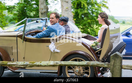 Bride and Groom voyageant dans une vieille voiture le jour de leur mariage. Heureux couple. Se marier au Royaume-Uni. Les jeunes mariés. Juste mariés. Banque D'Images