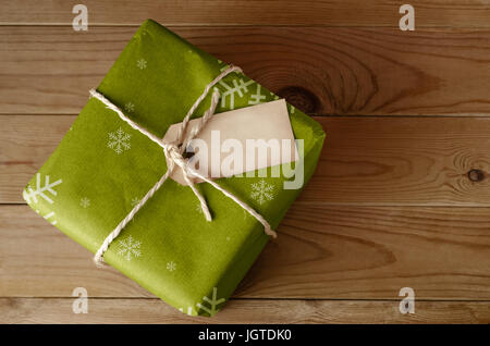 Passage tiré d'un colis de Noël vert enveloppé avec Motif flocon, liés avec de la ficelle. Visages étiquette vierge vers le haut pour fournir une copie de l'espace. Situé sur Banque D'Images