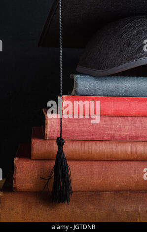 Une pile de vieux livres, utilisé vintage, disposées en étapes conduisant à une graduation cap en haut (mortier). Banque D'Images