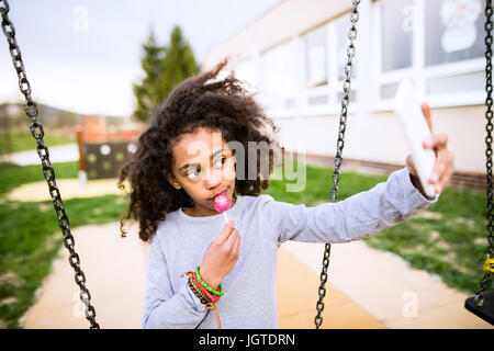 African American Girl with lollipop en tenant avec smartphon selfies Banque D'Images