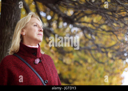 Senior woman in autumn park sur fond d'arbre jaune Banque D'Images