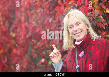 Happy smiling woman in autumn park sur fond de feuilles rouges Banque D'Images