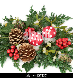 Décoration de Noël avec le houx, fly, ornements de champignons agaric des cônes de pin d'or, le gui et verdure d'hiver sur fond blanc. Banque D'Images