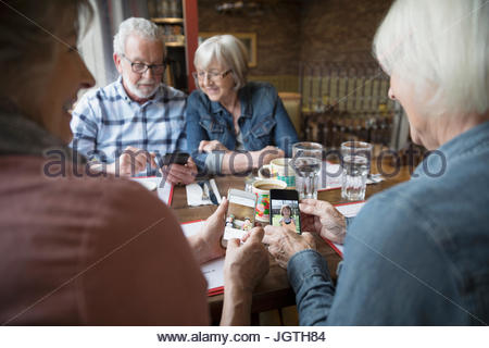 Les femmes âgées amis échangeant des photos numériques, des petits-enfants sur les téléphones avec appareil photo booth in diner