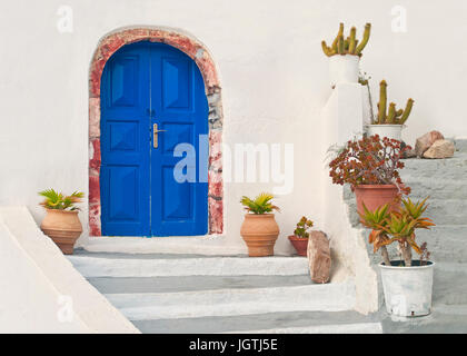 Porte bleue de belle maison grecque blanc avec des pots de fleurs sur les escaliers dans la ville d'Oia, Santorin (thira), Grèce Banque D'Images
