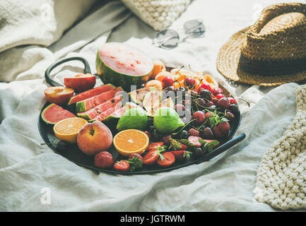 Été végétalien premières sain de manger le petit déjeuner au lit propre concept. Le bac plein de fruits frais de saison plus de couverture léger background, selective focus Banque D'Images