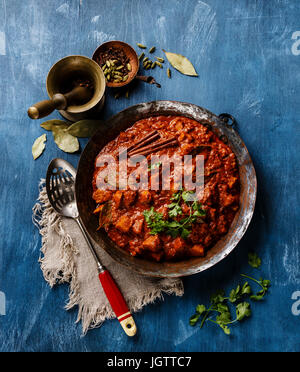 Poulet tikka masala curry indien épicé dans une casserole en cuivre sur fond de bois bleu Banque D'Images