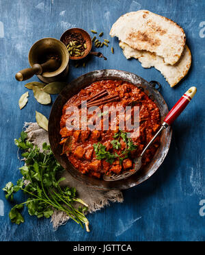 Poulet tikka masala curry indien épicé dans une casserole en cuivre sur fond de bois bleu Banque D'Images