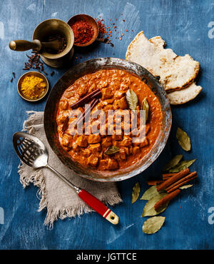 Poulet tikka masala curry indien épicé dans une casserole en cuivre sur fond de bois bleu Banque D'Images