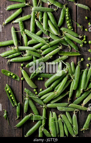 Les jeunes gousses de pois vert et pois de vieilles planches en bois sombre arrière-plan. Vue de dessus avec l'espace. La récolte, l'alimentation saine. Banque D'Images