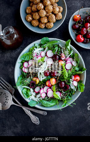 Salade de riz sauvage cerise Vinaigrette avec Hibiscus servi avec du vin blanc. Photographié sur un fond gris/noir. Banque D'Images