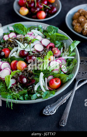 Salade de riz sauvage cerise Vinaigrette avec Hibiscus servi avec du vin blanc. Photographié sur un fond gris/noir. Banque D'Images