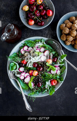 Salade de riz sauvage cerise Vinaigrette avec Hibiscus servi avec du vin blanc. Photographié sur un fond gris/noir. Banque D'Images
