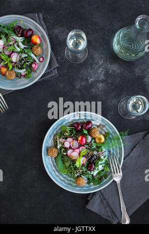 Salade de riz sauvage cerise Vinaigrette avec Hibiscus servi avec du vin blanc. Photographié sur un fond gris/noir. Banque D'Images