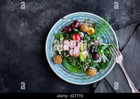 Salade de riz sauvage cerise Vinaigrette avec Hibiscus servi avec du vin blanc. Photographié sur un fond gris/noir. Banque D'Images