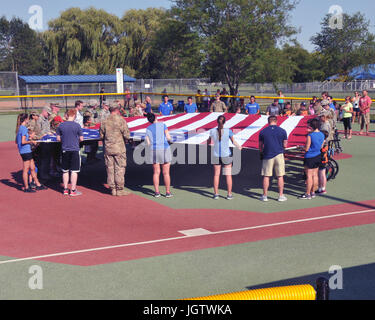 Des membres de la Delta Company, du 334e bataillon de soutien de brigade, de la Garde nationale de l'armée de l'Iowa, ainsi que des athlètes et des amis de la Sioux City Miracle League, ont soutenu le drapeau américain lors de l'hymne national lors de leur match All-Star le 9 juillet 2017 à Sioux City, Iowa. Les membres de la Ligue miracle sont nommés gardiens honoraires pour l'événement. Banque D'Images