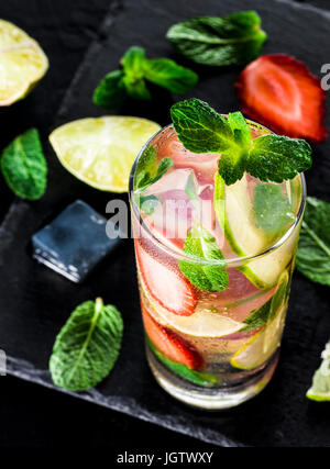 Limonade Fraîche avec fraise, menthe et citron vert foncé sur fond de pierre. Boisson fraise d'été froid à la menthe et de la glace. Mojito en verre et Banque D'Images