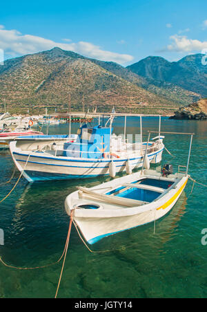 Le moteur est blanc petits bateaux amarrés au quai dans village crétois de Bali entouré de montagnes sur soirée ensoleillée, Crète, Grèce Banque D'Images