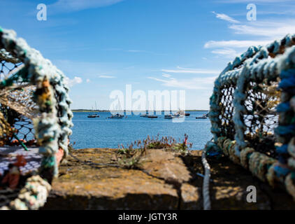 Les cages en filet de pêche du homard dans un mur du port avec vue sur le port en bateau Banque D'Images