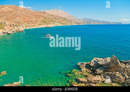 Petite bateau touristique sur la plage des palmiers dans des eaux cristallines de la Méditerranée en Crète, Grèce Banque D'Images
