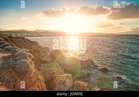 Vue sur la mer Méditerranée et de la ville côtière au coucher du soleil sur les roches, Crète, Grèce Banque D'Images