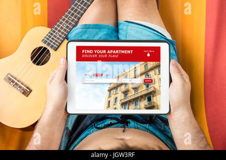 Jeune homme de visiter un appartement en location site web avec tablette, allongé sur un hamac. Banque D'Images