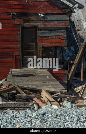 Une porte fermée repose sur les vestiges d'un bâtiment en bois revêtus de rouge. Banque D'Images