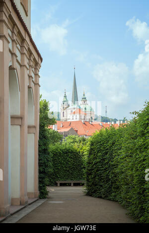 Bâtiment, clôture et bush green lane au jardin Wallenstein à la Ville basse de Prague. Saint Thomas l'Église et de l'église Saint Nicolas sont en arrière-plan. Banque D'Images