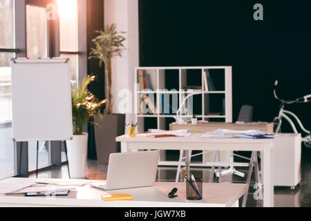 Lieu de travail vide avec un ordinateur portable, le bloc-notes et documents in modern office Banque D'Images