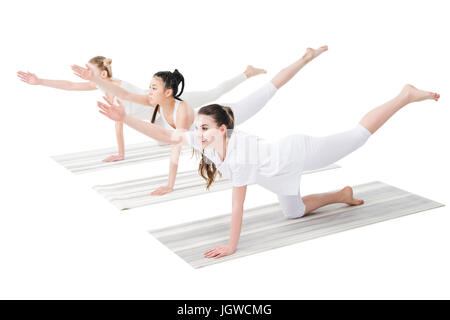 Smiling women pratiquer bird dog poser sur un tapis de yoga isolated on white Banque D'Images