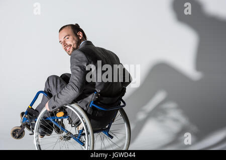 Les jeunes handicapés en fauteuil roulant d'affaires avec son ombre sur le mur Banque D'Images
