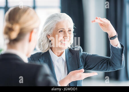 Senior businesswoman montrant quelque chose à collègue sur meeting in office Banque D'Images