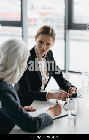 Two businesswomen with digital tablet discuter affaires projet sur meeting in office Banque D'Images