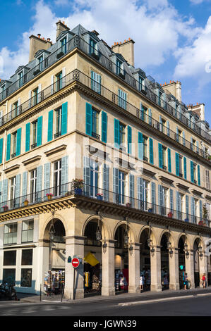 Un immeuble haussmannien typique à Paris avec balcons, volets, arcades et boutiques sous une lumière chaude de fin d'après-midi. Banque D'Images