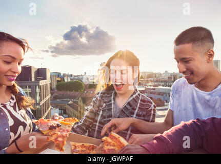 Les amis des jeunes adultes partageant une pizza à la partie du toit à Londres, Royaume-Uni Banque D'Images