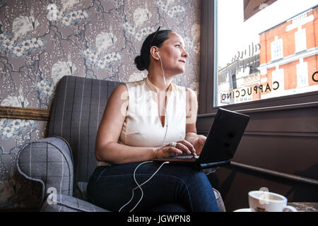 Businesswoman in coffee bar à la recherche d'une fenêtre avec portable Banque D'Images