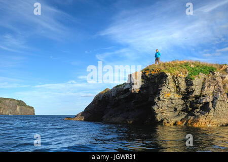 Mid adult woman looking out à partir de la falaise côtière, St John's, Terre-Neuve, Canada Banque D'Images