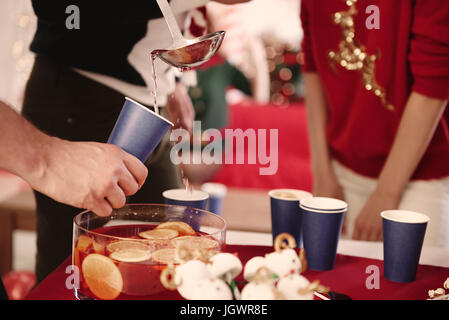 Cropped shot of young man servant à perforer les amis at Christmas party Banque D'Images